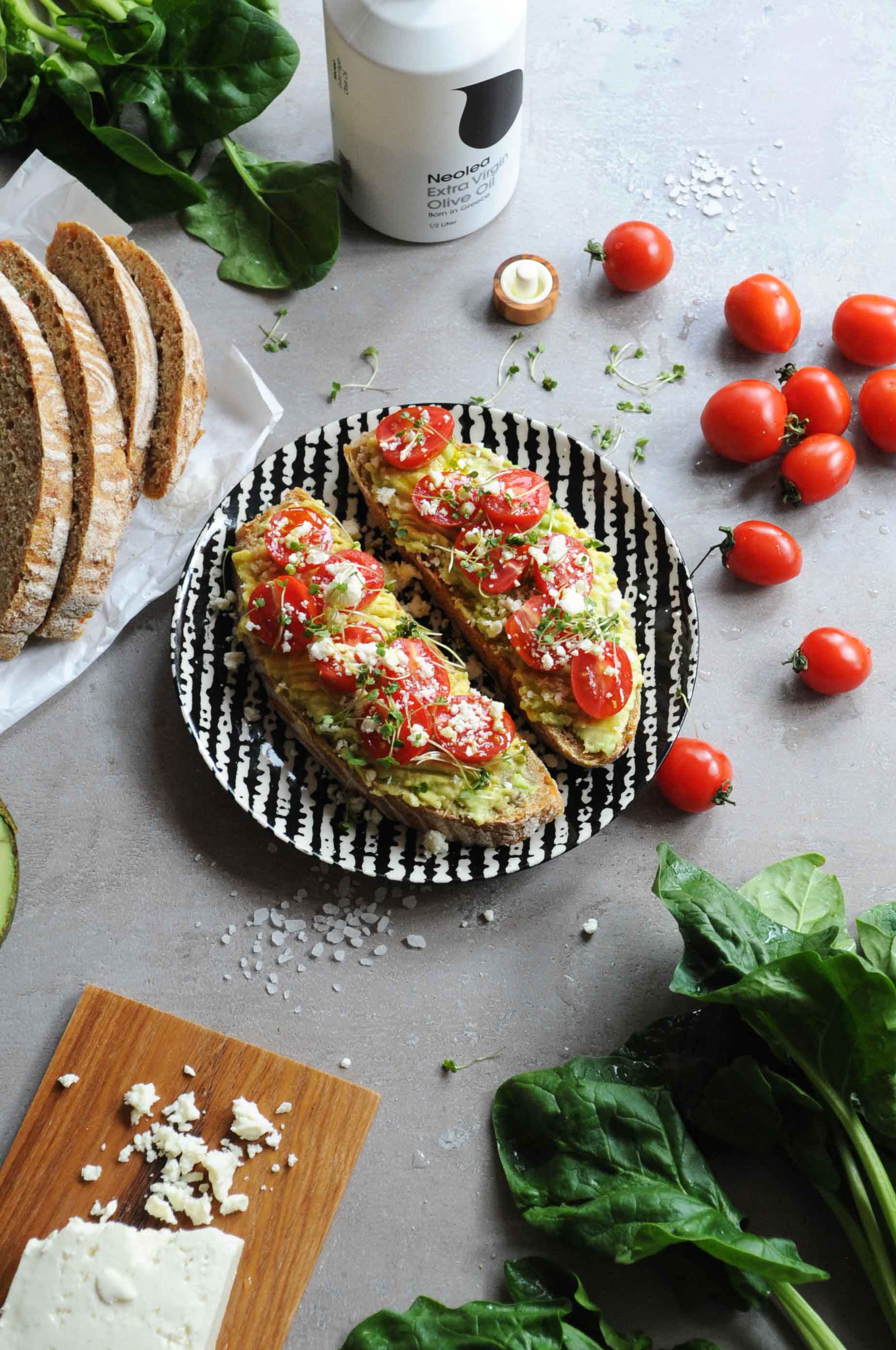 Avocado toast with feta cheese, cherry tomatoes and microgreens on toasted sourdough bread