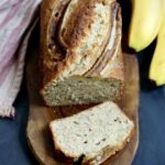 Moist homemade banana bread with a golden crust and ripe bananas, sliced and ready to serve.