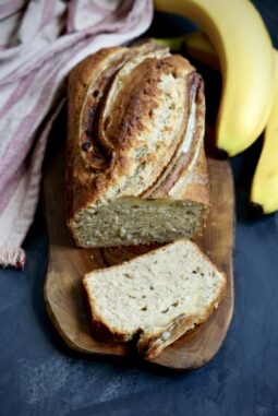 Moist homemade banana bread with a golden crust and ripe bananas, sliced and ready to serve.