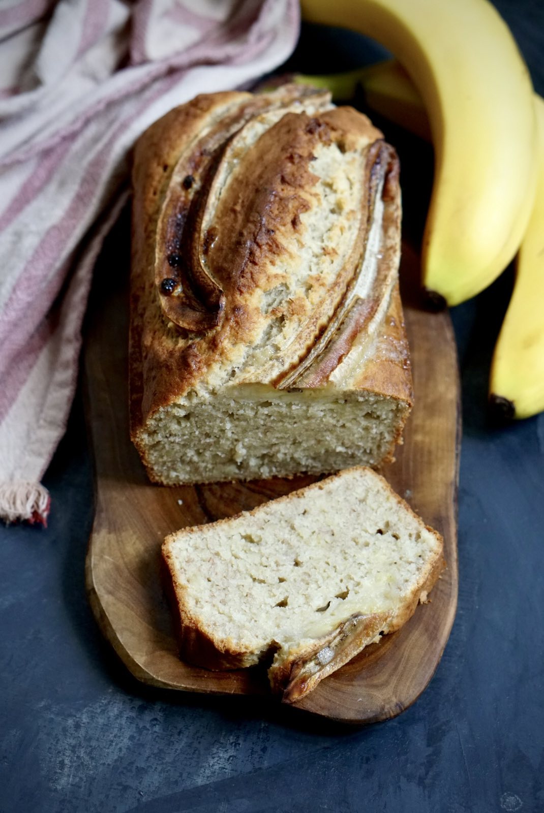 Moist homemade banana bread with a golden crust and ripe bananas, sliced and ready to serve.