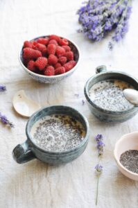 Chia pudding made with almond milk before refrigerating, topped with fresh raspberries and chia seeds.