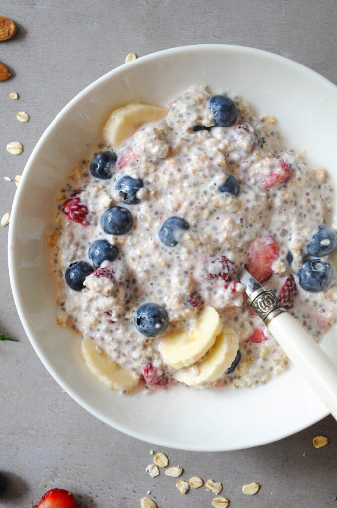 Creamy almond milk overnight oats with bananas, strawberries, and blueberries