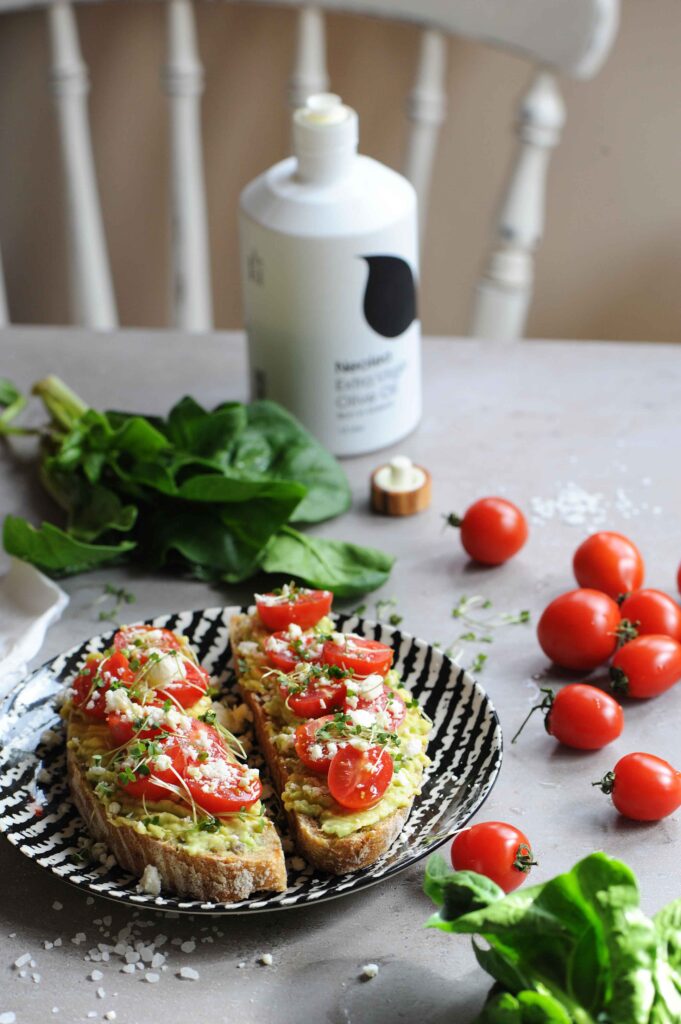Healthy avocado toast with feta cheese, cherry tomatoes and microgreens served on toasted sourdough bread