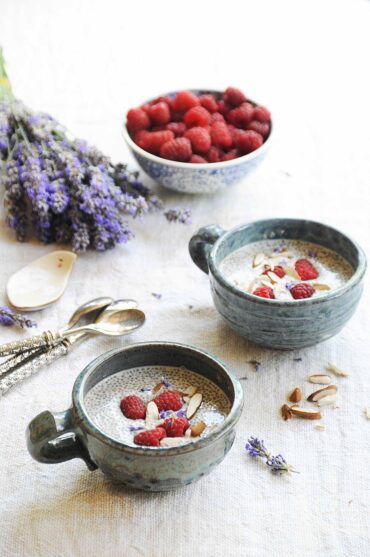 Creamy almond milk chia pudding with fresh raspberries, chia seeds, and coconut flakes served in ceramic bowls.