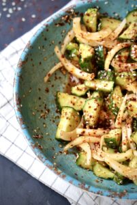 Close-up of Korean Cucumber Salad (Oi Muchim) with crisp cucumbers, onions, sesame seeds, and gochugaru.
