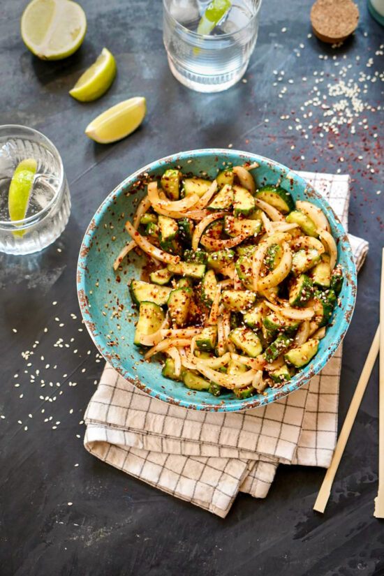 Korean Cucumber Salad (Oi Muchim) served in a blue bowl with sesame seeds and spicy gochugaru.