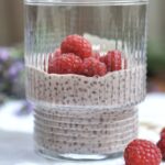 Protein chia pudding with coconut milk topped with fresh raspberries in a glass