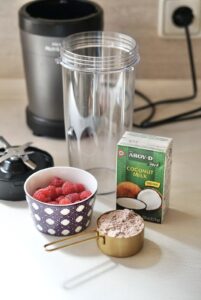 Empty blender jar ready to mix protein powder, coconut milk, and raspberries for chia pudding