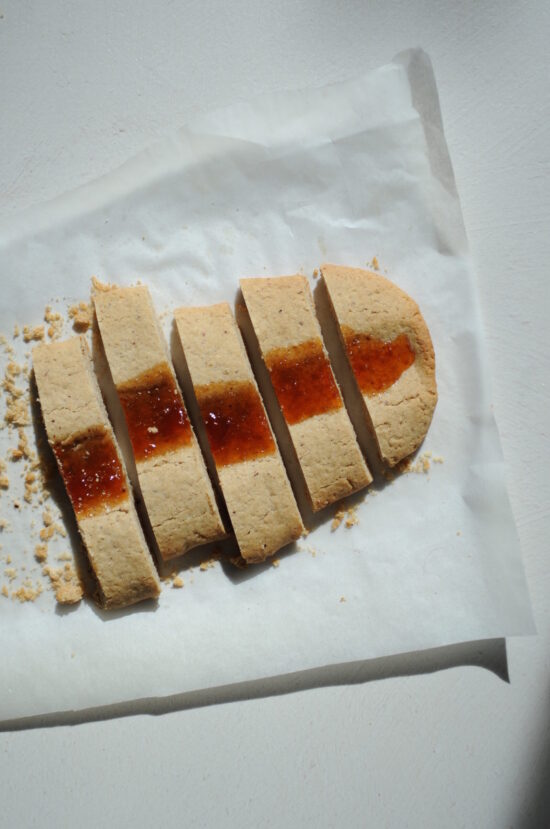 Sliced almond jam ribbon cookies arranged on parchment paper