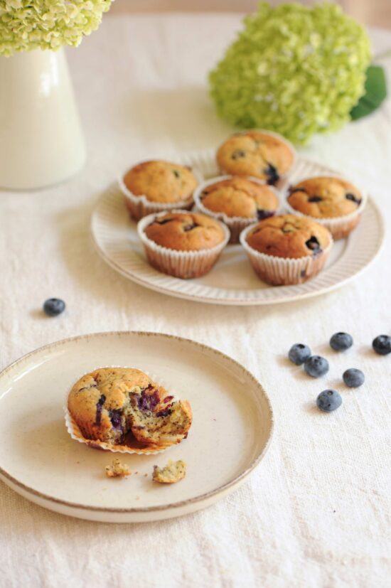 Blueberry lemon poppy seed muffins served on a table with fresh flowers and scattered blueberries