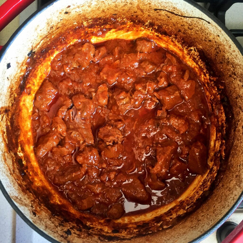 Fork-tender braised beef in tomato sauce after slow cooking in a Dutch oven