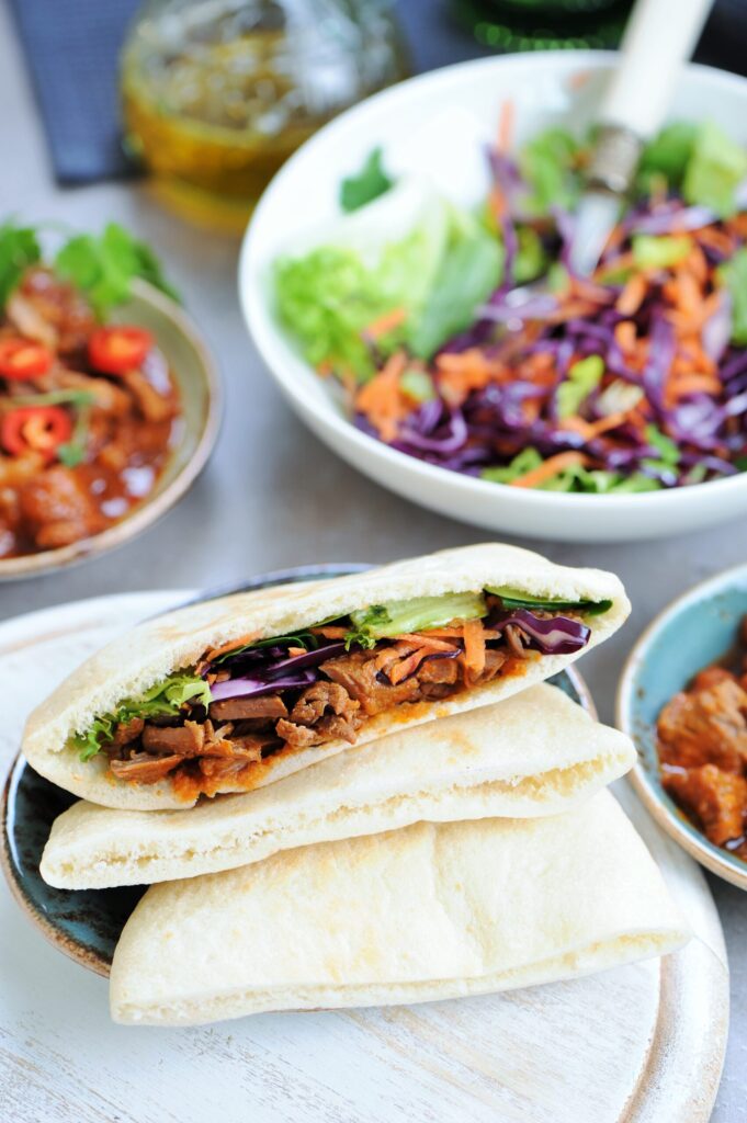 Pita sandwich filled with braised beef, hummus, and crunchy cabbage salad