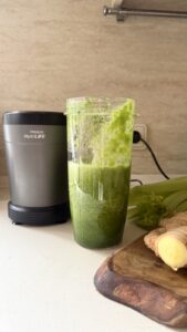 Celery apple green smoothie with ginger blended in a glass blender jar, showing the vibrant green color of the drink