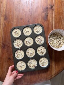 Cherry buttermilk muffin batter topped with sliced almonds in a muffin pan
