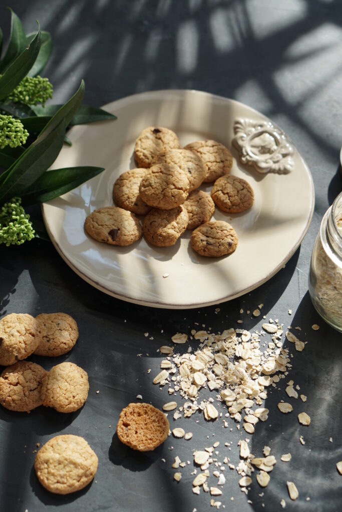 Homemade oatmeal chocolate chip cookies on a plate with rolled oats
