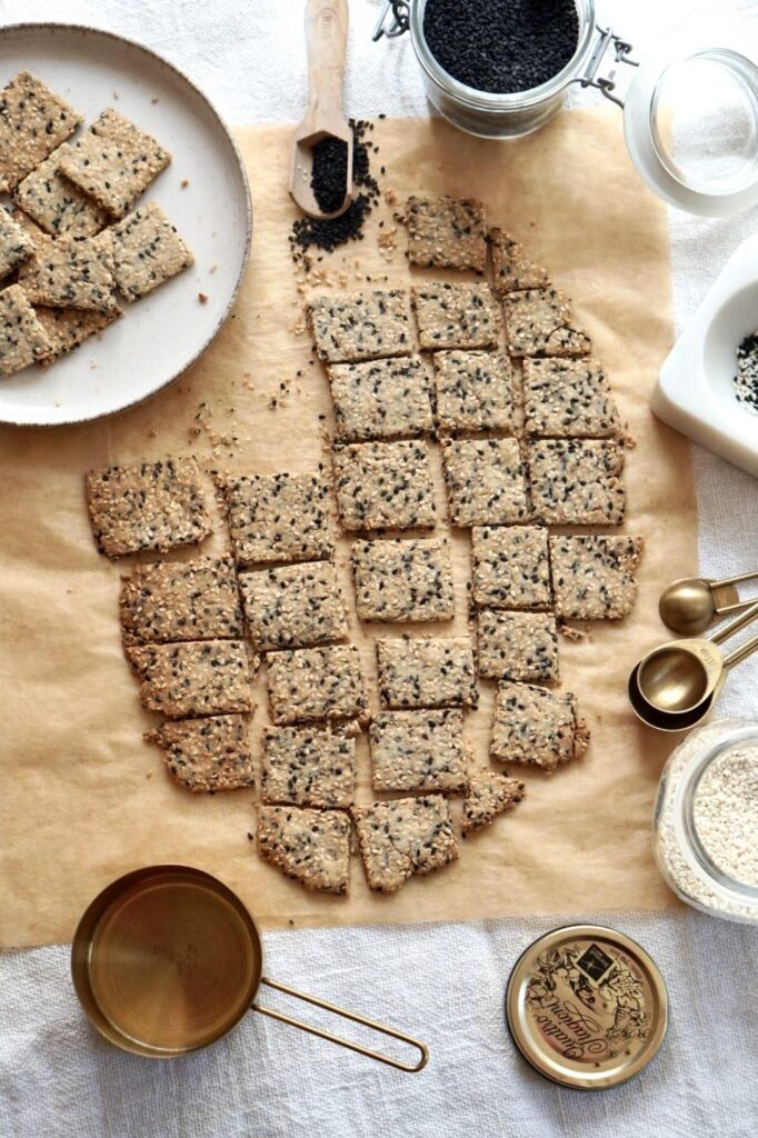 Gluten-free almond flour crackers with white and black sesame seeds on parchment paper