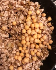 Ground beef sautéing in a pan with chickpeas and diced eggplant filling