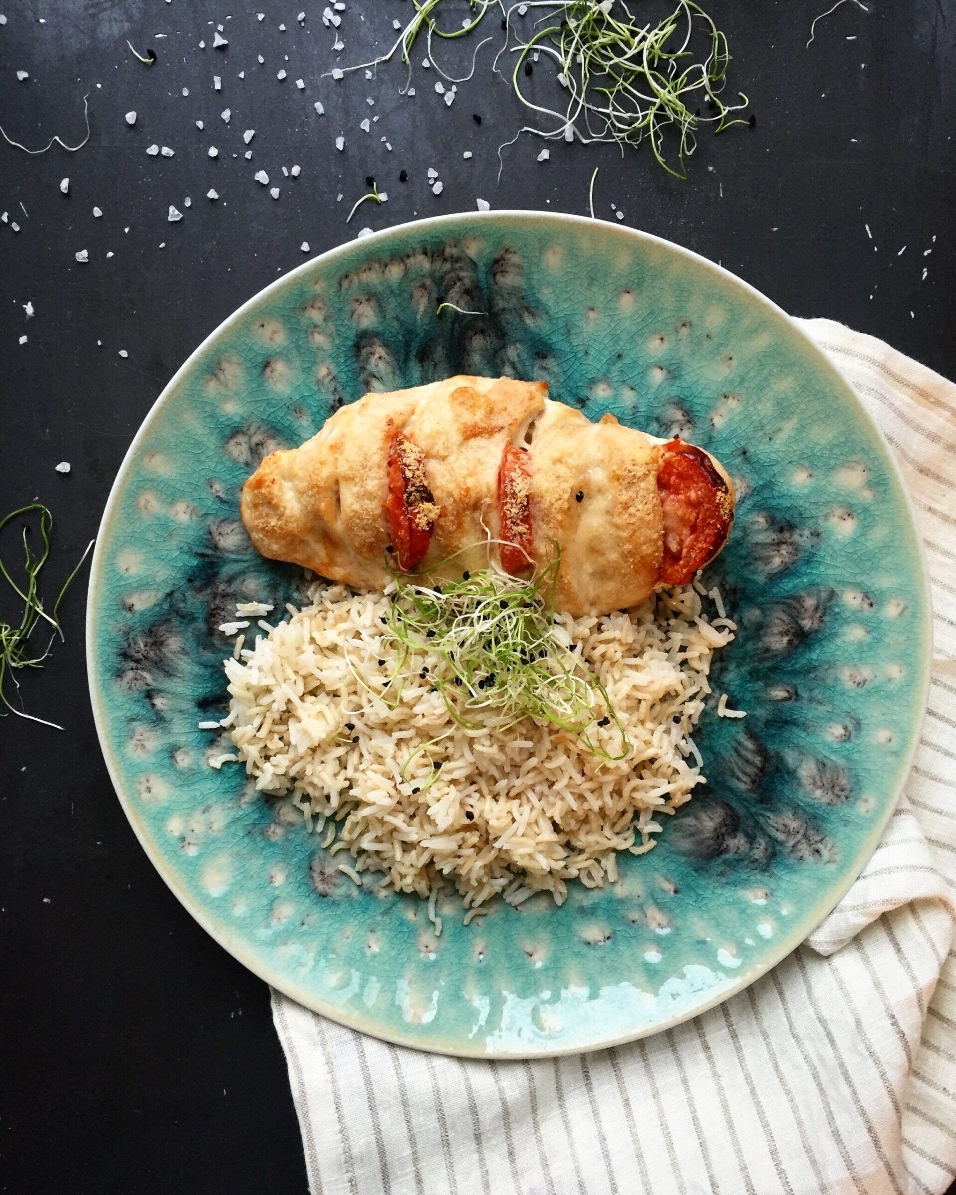 Plated Hasselback chicken breast with mozzarella and tomatoes served alongside a mix of basmati and wild rice