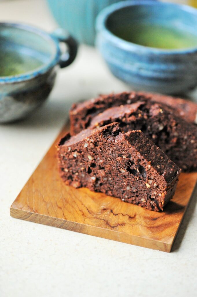 Slices of homemade chocolate almond loaf cake served on a wooden cutting board