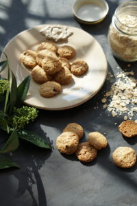 Homemade oatmeal chocolate chip cookies with rolled oats on a dark table