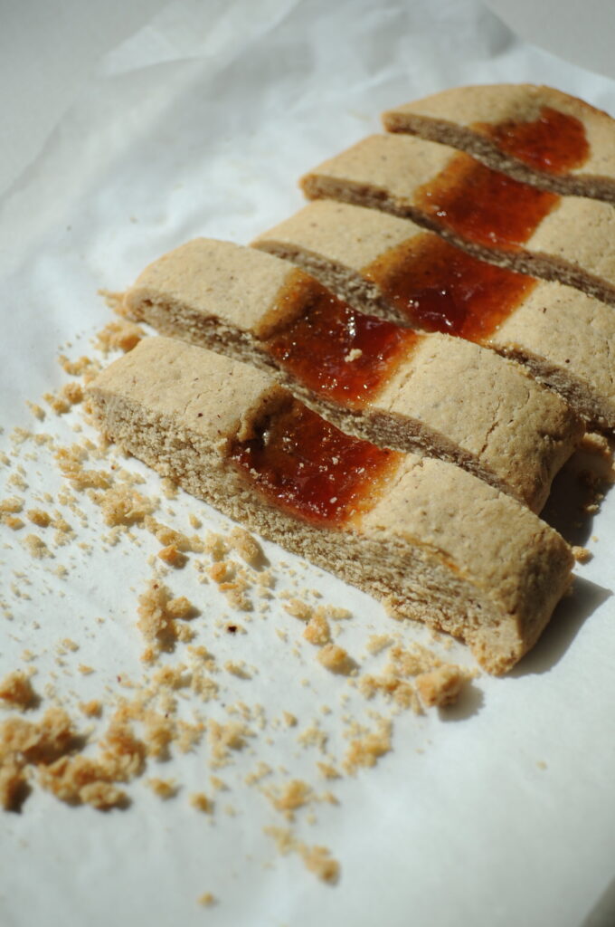 Close-up of sliced almond jam ribbon cookies filled with fruit jam