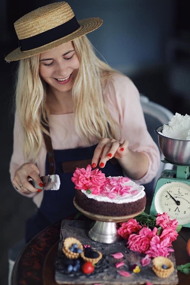 Olga Bux, creator of Weeknight Flame, decorating a chocolate cake with pink flowers