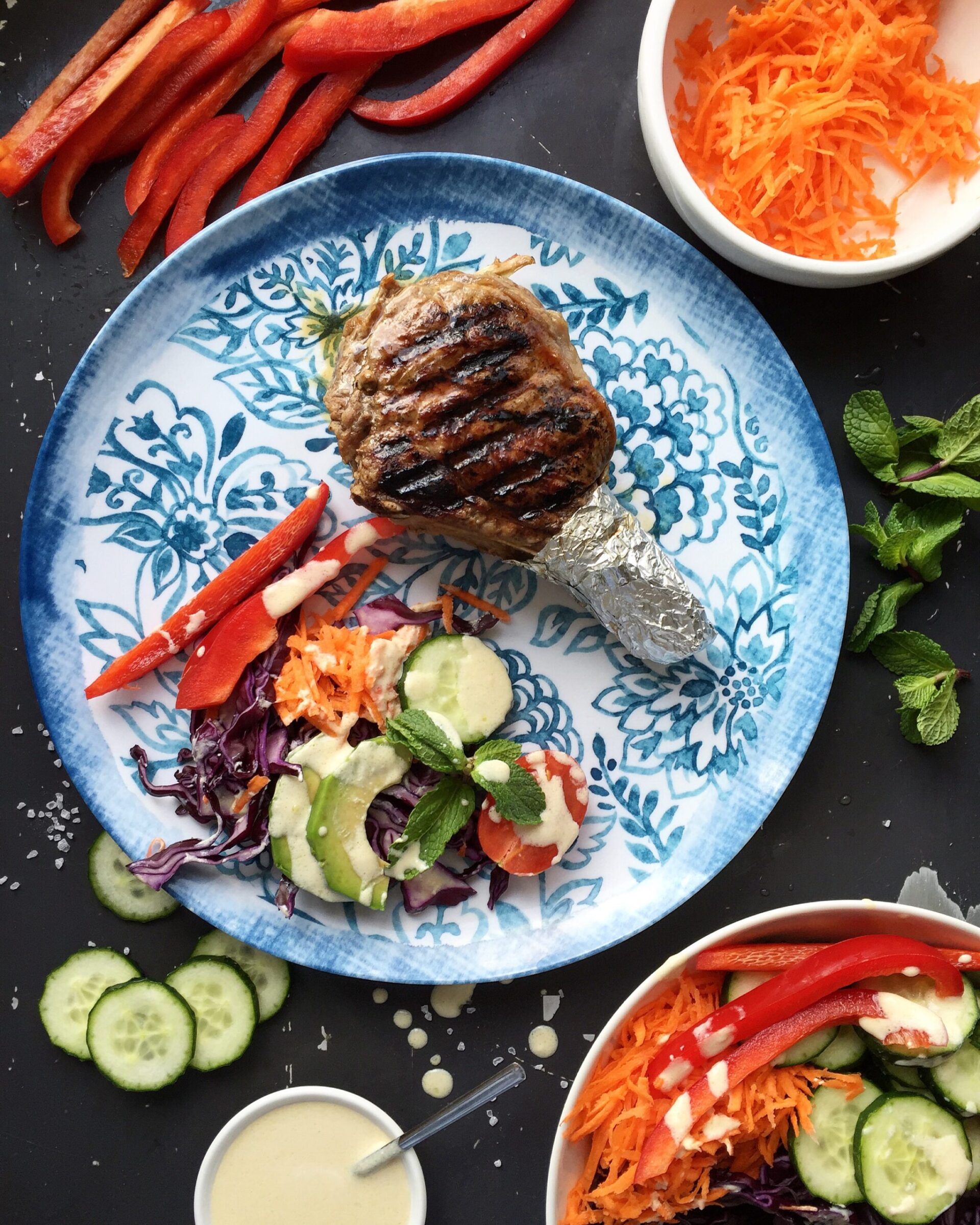 Pan-seared bone-in steak served with a rainbow vegetable salad