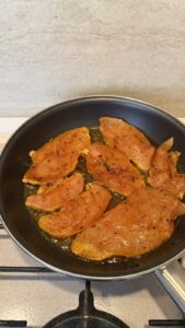 Chicken breast pieces pan-searing in a skillet until golden brown