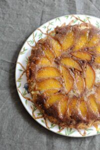 A slice of homemade peach upside-down cake with golden caramel glaze.