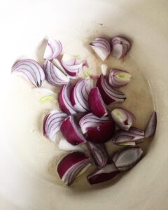 Sliced red onions in a bowl for creamy pumpkin soup
