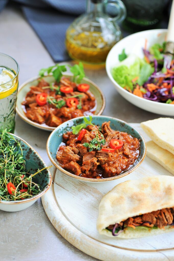 Slow-braised beef in tomato sauce served with cabbage salad and warm pita