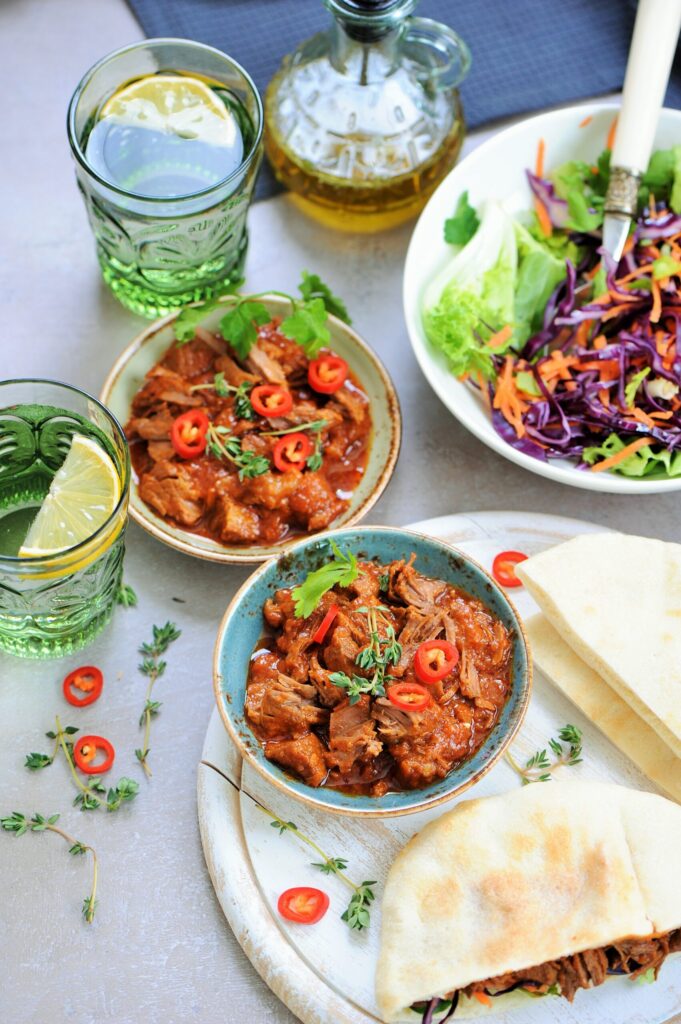 Tender braised beef with tomato sauce, pita bread, and fresh cabbage salad