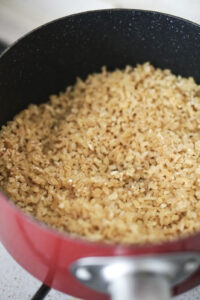 Bulgur wheat toasting in a dark skillet with melted butter and olive oil.