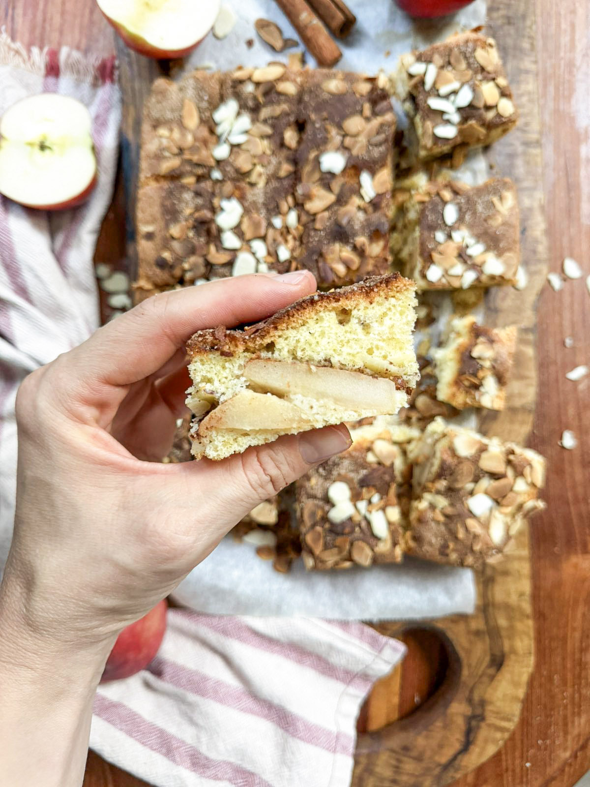 Hand holding a slice of apple charlotte cake showing soft apple layers inside