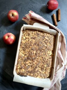 Overhead view of apple charlotte cake with cinnamon sticks and fresh apples