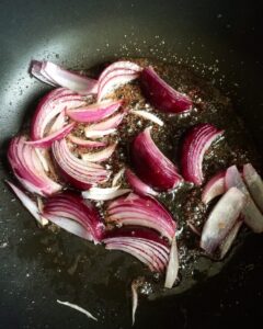 Red onions caramelizing in a skillet with balsamic vinegar