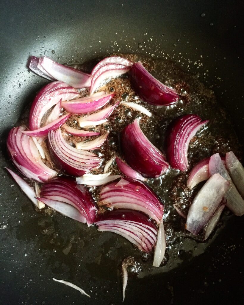 Red onions caramelizing in a skillet with balsamic vinegar