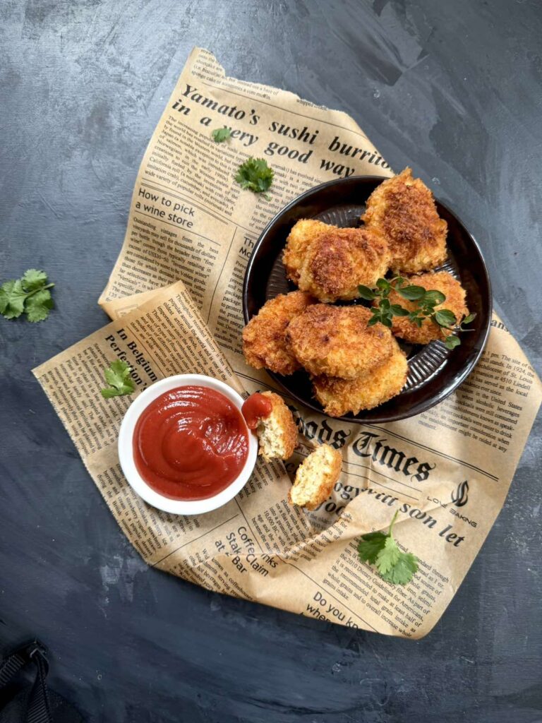 Overhead view of a plate of golden chicken nuggets with ketchup and fresh parsley.