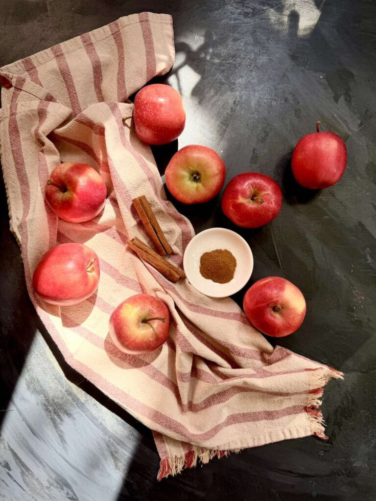 Fresh red apples with cinnamon sticks on a striped kitchen towel