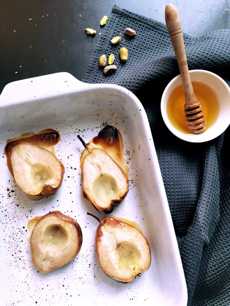 Honey-baked pear halves in a baking dish after roasting