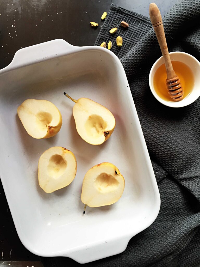 Cored pear halves arranged in a baking dish before baking
