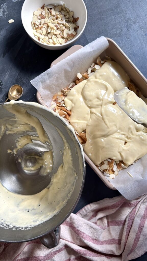 Pouring cake batter over a layer of apples and almonds in a baking pan