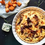 Baked pumpkin quiche with blue cheese and caramelized red onions, styled with roasted pumpkin cubes