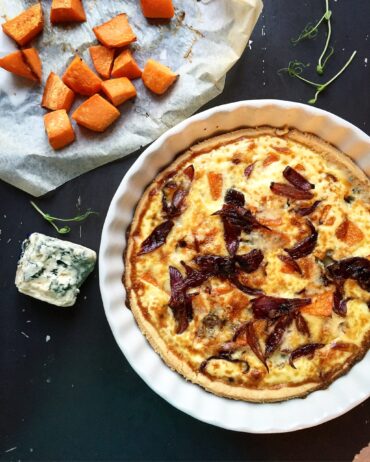 Baked pumpkin quiche with blue cheese and caramelized red onions, styled with roasted pumpkin cubes