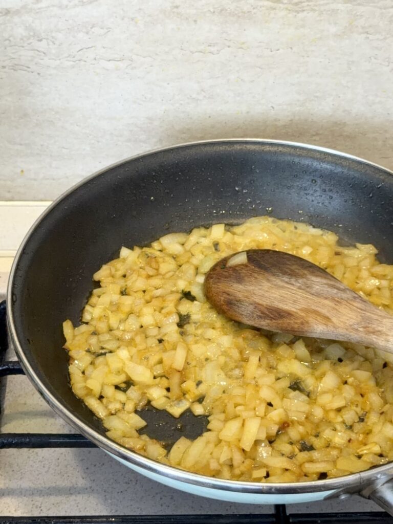Chopped onions sautéing in a skillet for the coconut Tom Yum sauce.