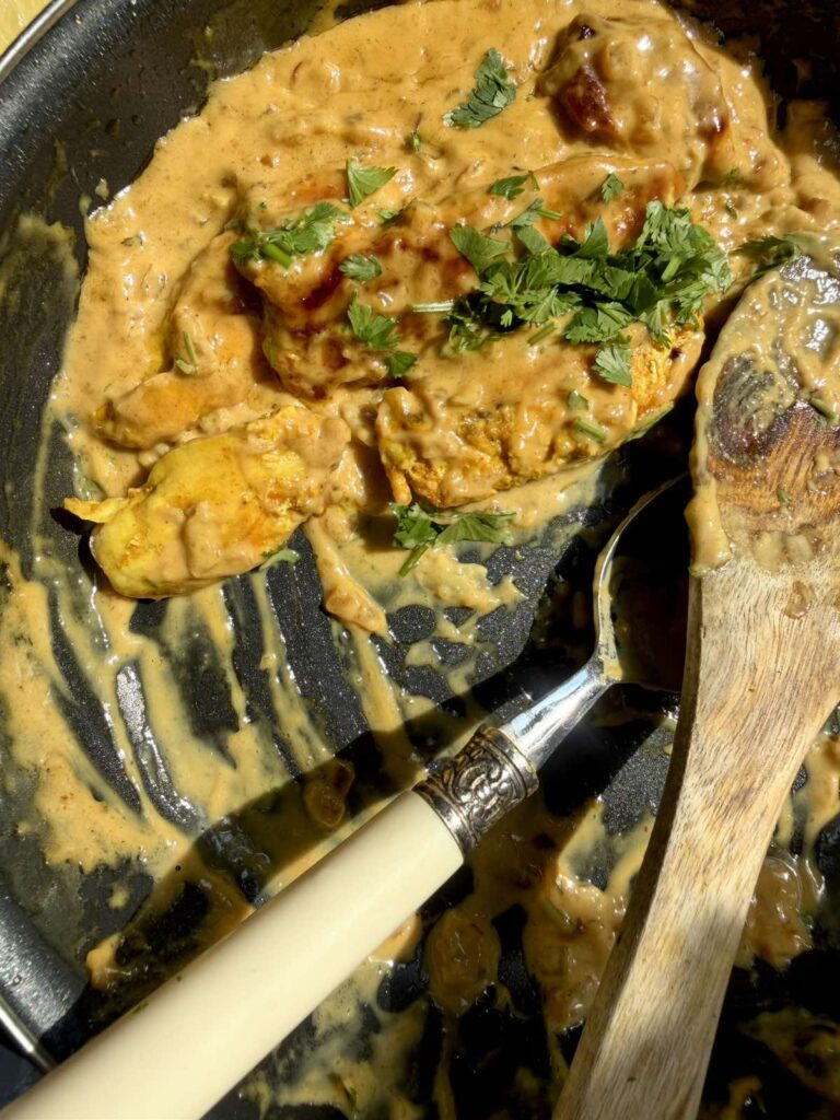 Stirring chicken pieces into the coconut milk and Tom Yum sauce.