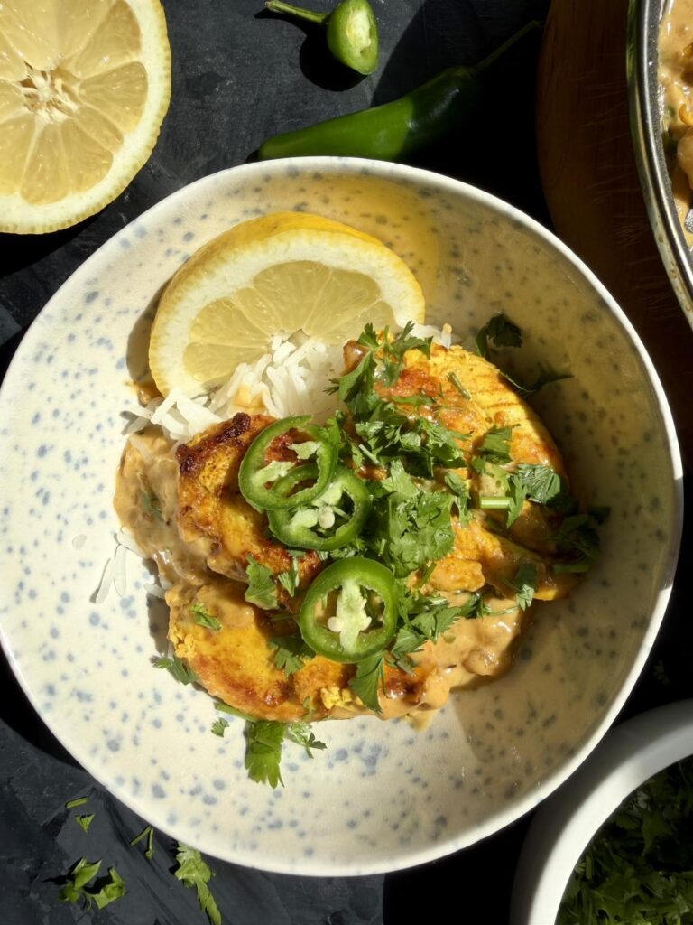 Close-up of Tom Yum chicken and coconut milk sauce served over white rice.