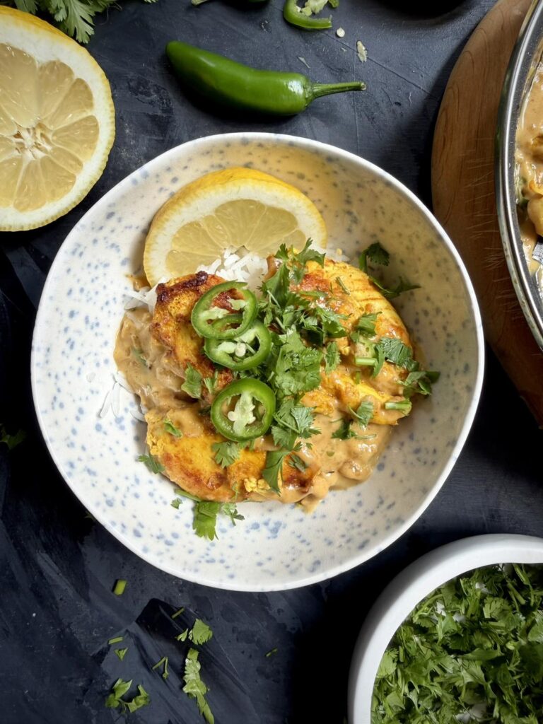 Tom Yum chicken served over white rice with cilantro and sliced green chili.