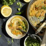 Tom Yum chicken in coconut milk sauce served over rice with cilantro and sliced green chili.