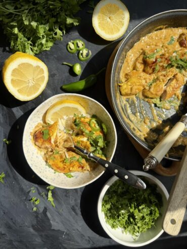 Tom Yum chicken in coconut milk sauce served over rice with cilantro and sliced green chili.